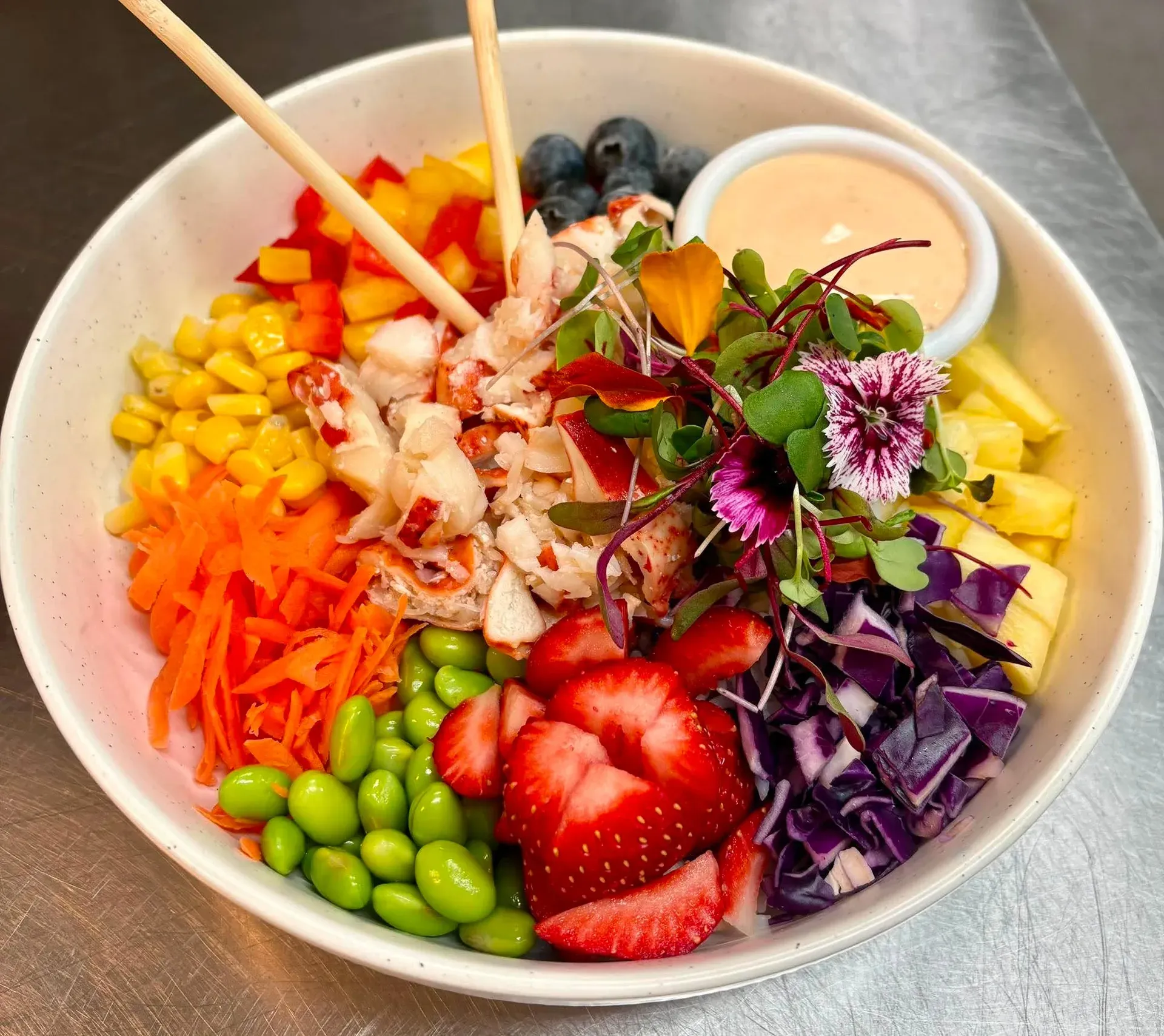 Poke bowl au homard avec fraises, edamames, maïs, carotte, chou rouge et fleurs comestibles